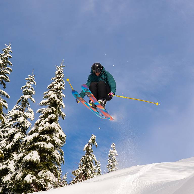Skier jumping over snow on a bluebird day.