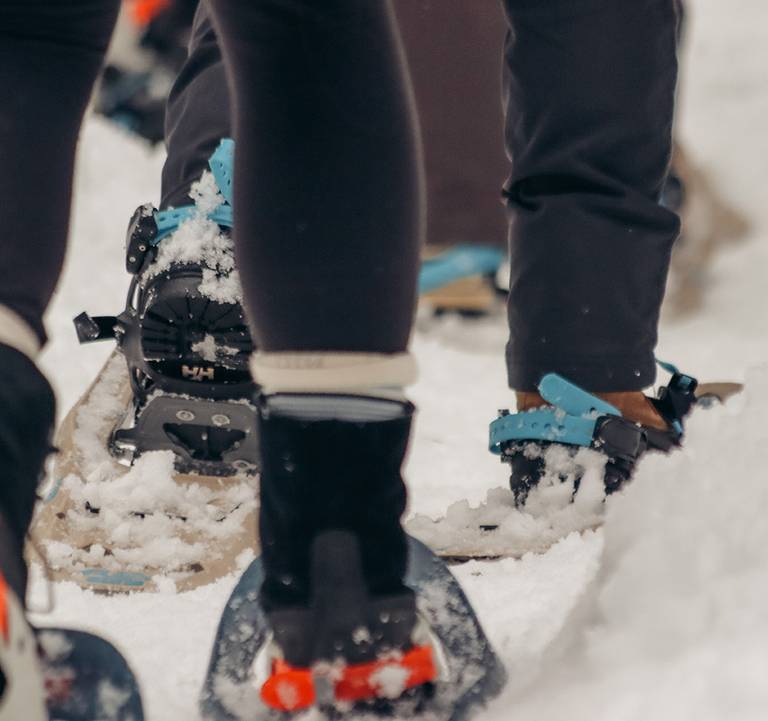 Closeup of people walking in snowshoes.