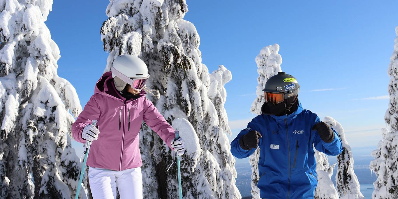 Snowboard instructor teaching a student how to ski a green run on Cypress Mountain resort.
