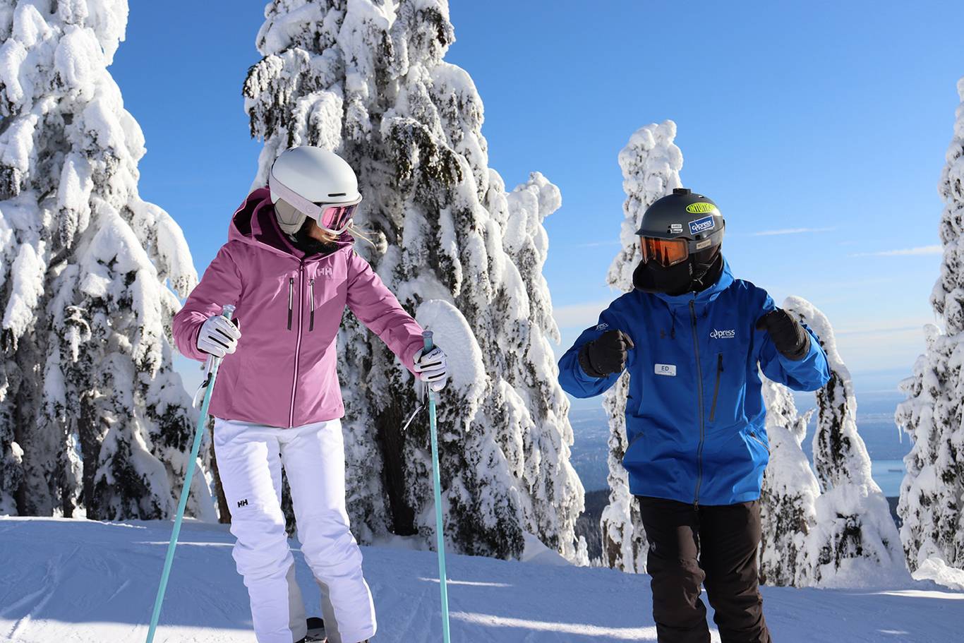 Instructor and adult skier in front of snowy trees