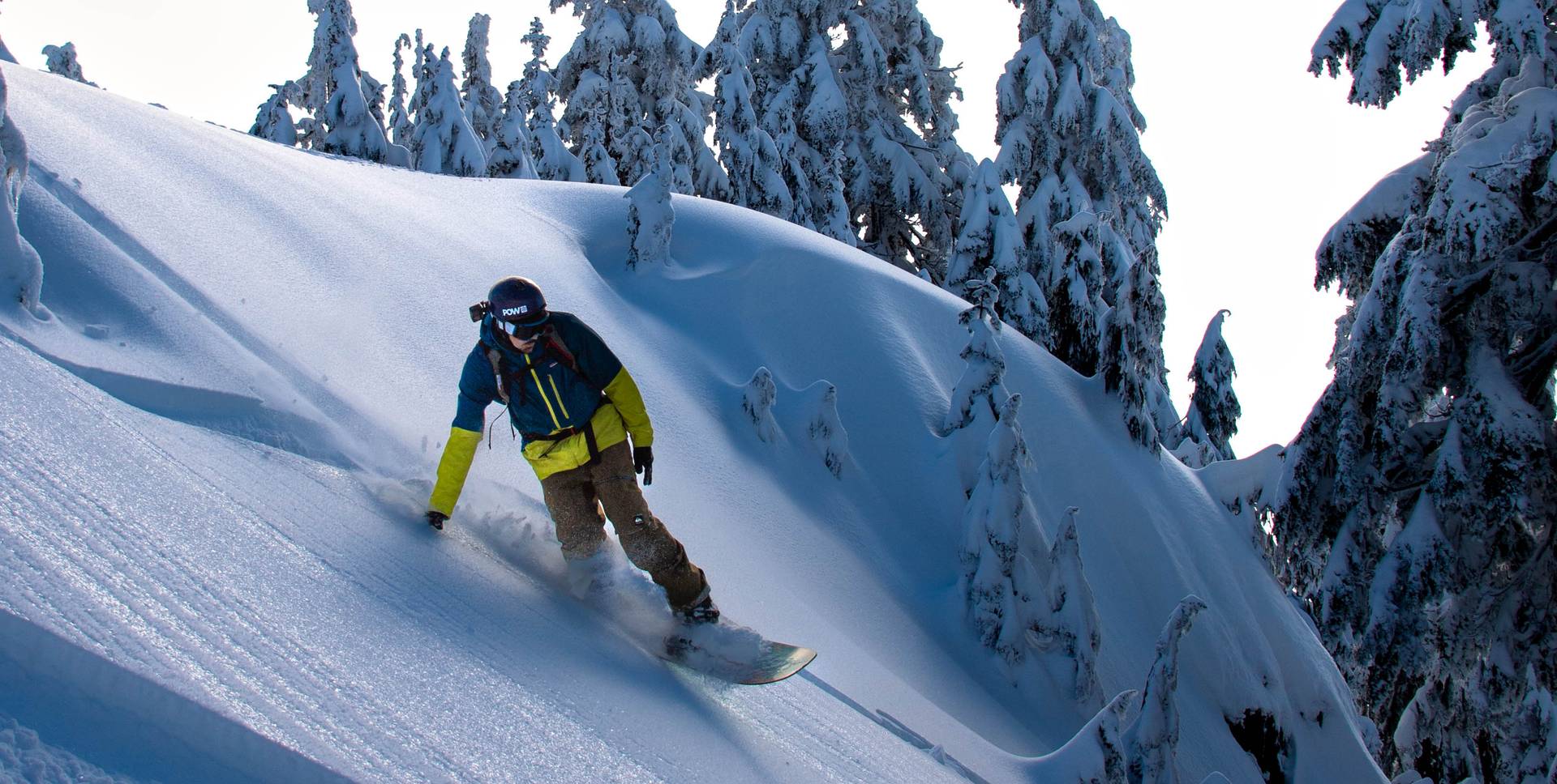 Snowboarder riding down on fresh snow.