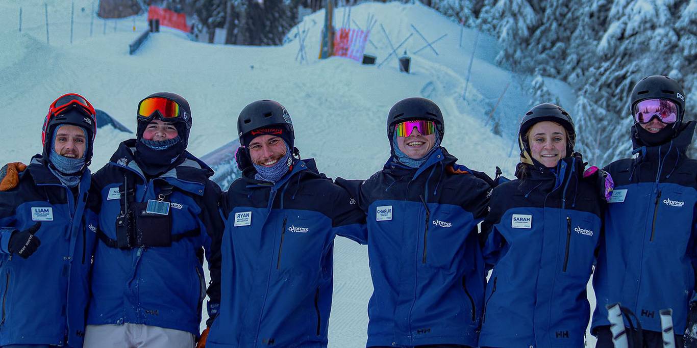 Terrain park patrollers and lift operators smile in front of a terrain park.
