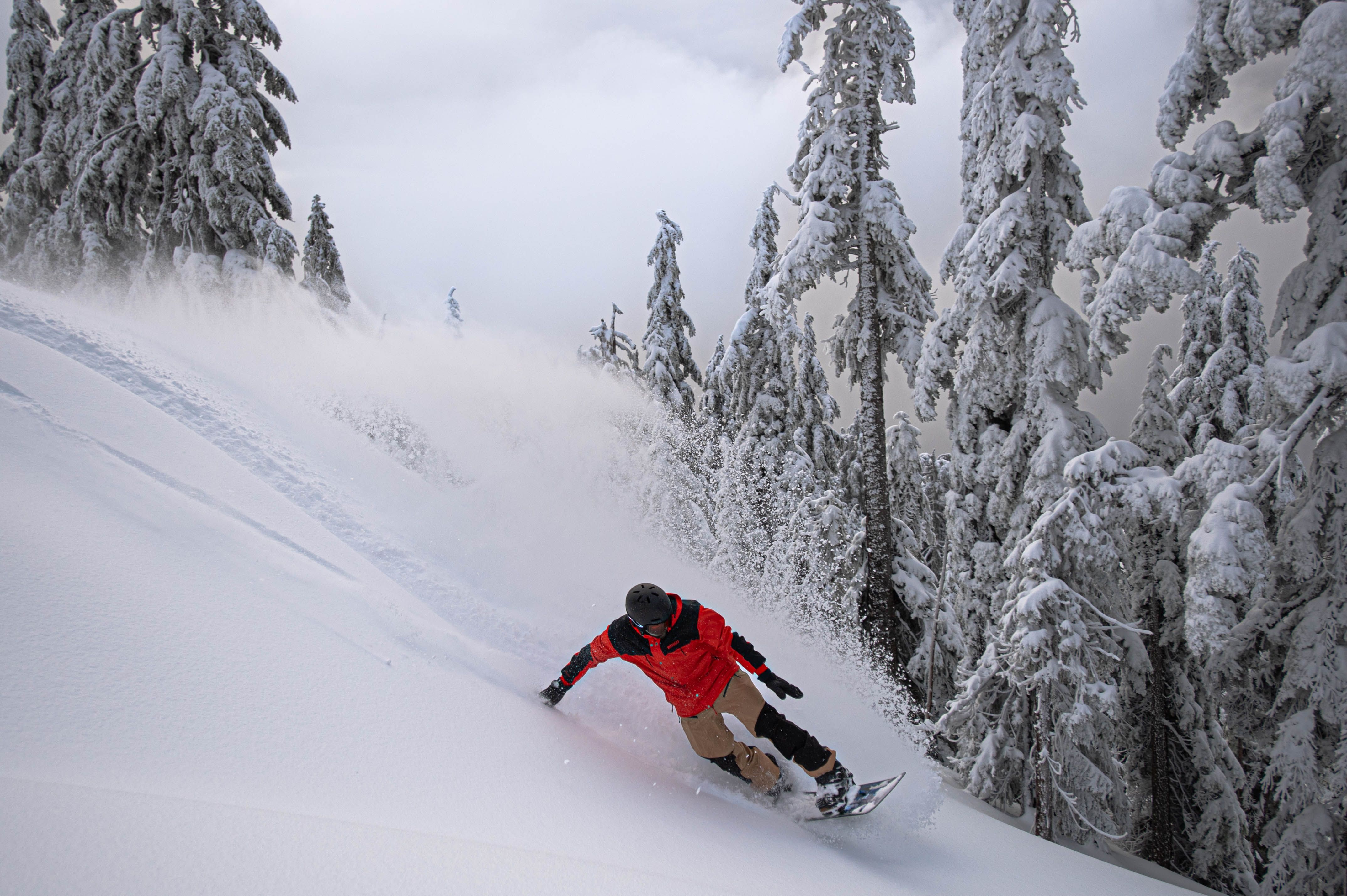 Snowboarder with red jacket on a powder day.