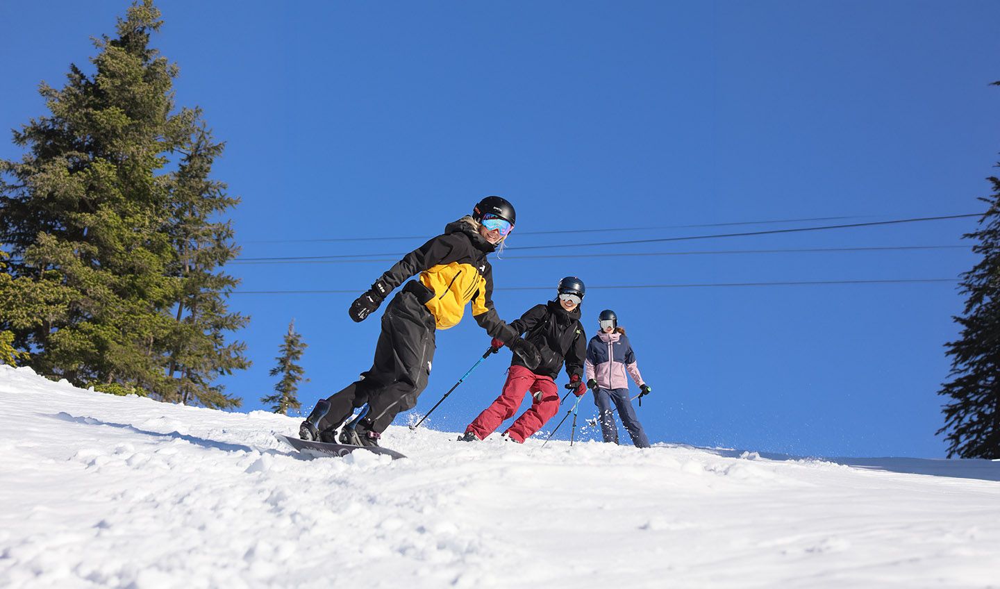 Two skiers and one snowboarder on a bluebird day.
