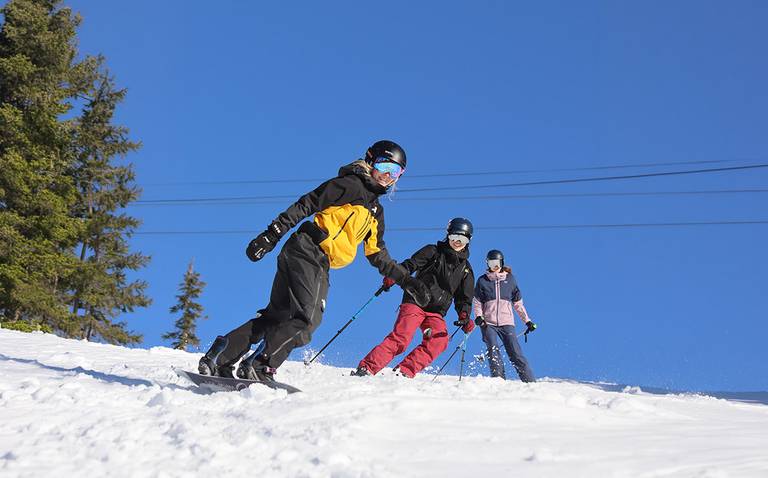 Two skiers and one snowboarder on a bluebird day.
