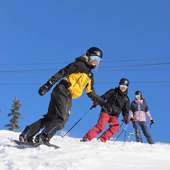Two skiers and one snowboarder on a bluebird day.