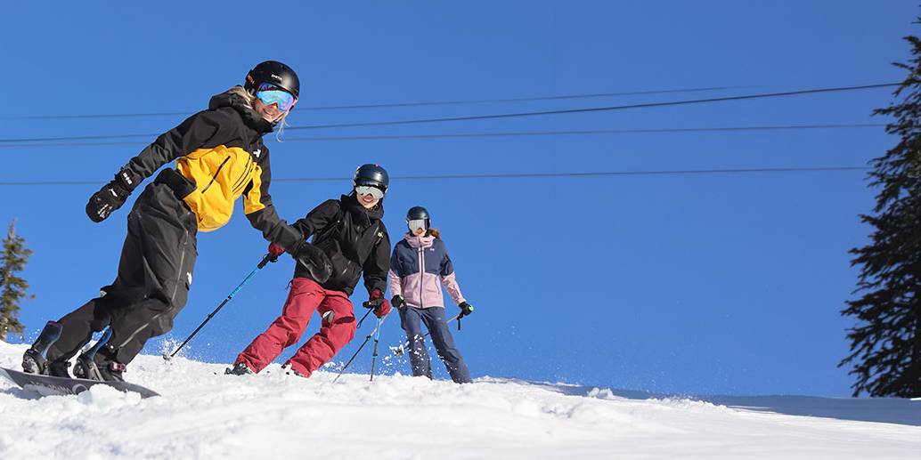 3 women skiing and riding down Sky Chair on a bluebird day
