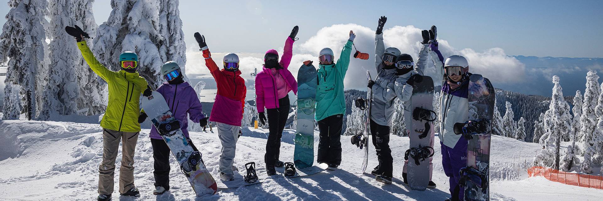 A group of women pose with skies and snowboards on top of Cypress Mountain.
