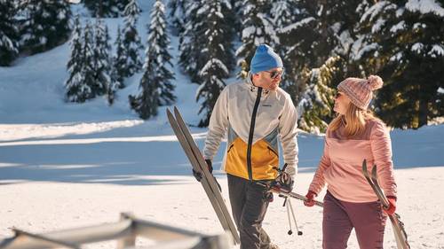 Cross country skier couple walking and smiling at each other.