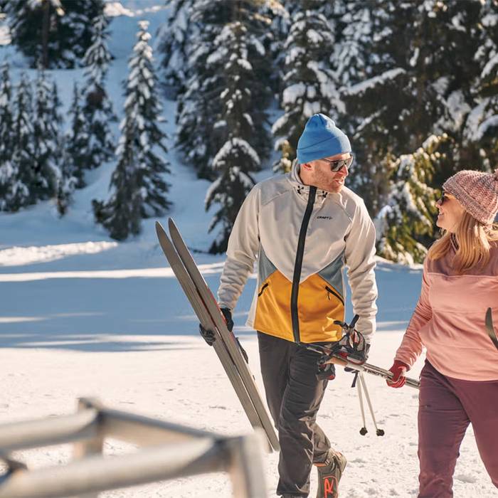 Cross country skier couple walking and smiling at each other.
