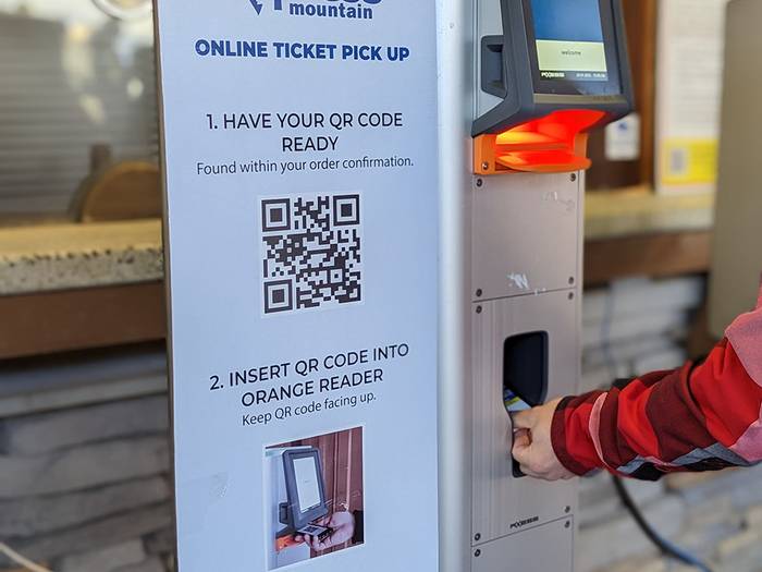 Person getting their ticket from a kiosk.