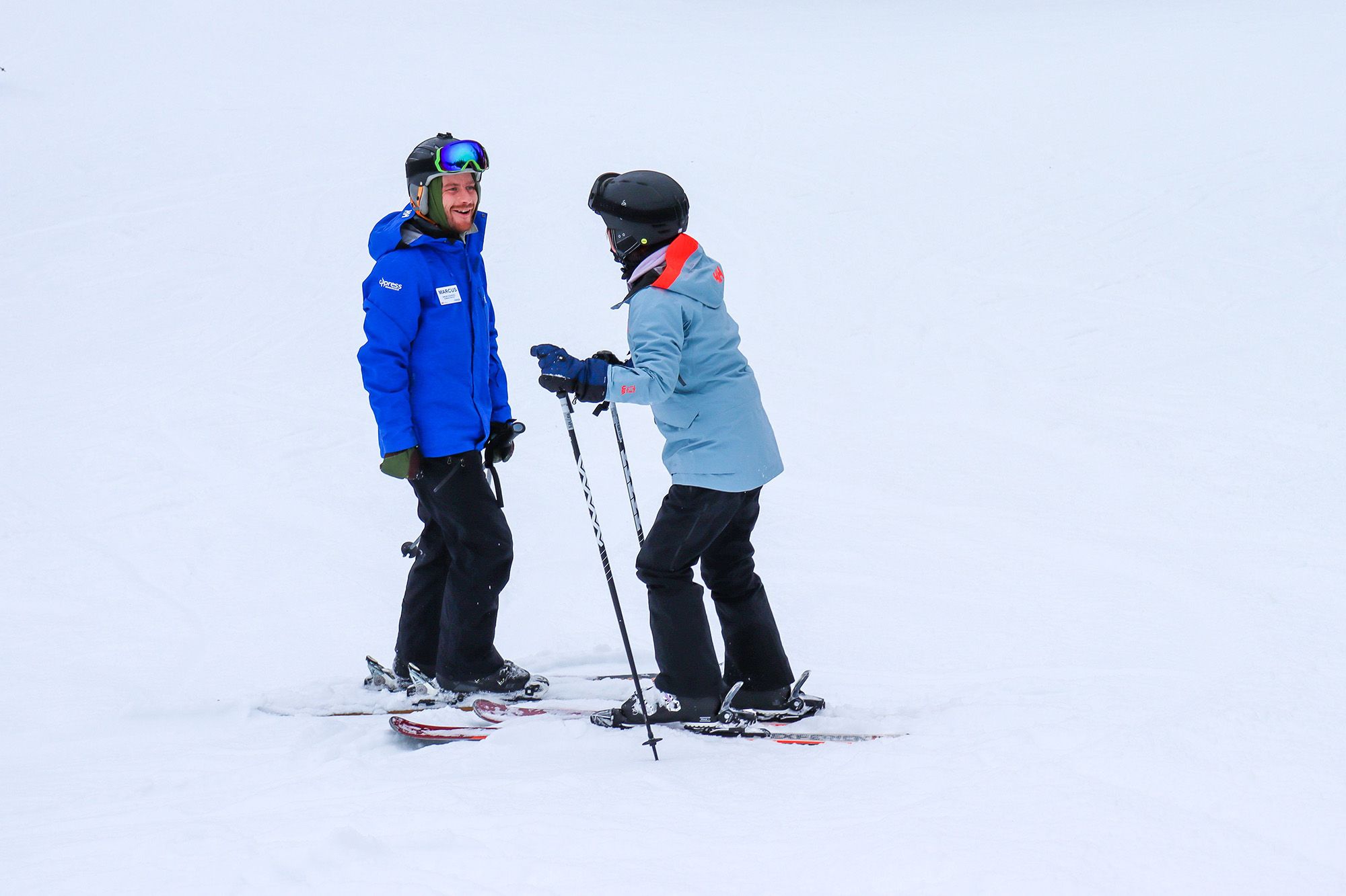 An instructor teaching an adult how to ski.