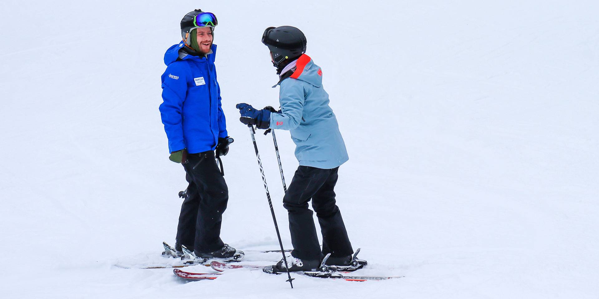 An instructor teaching an adult how to ski.