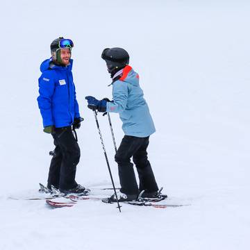 An instructor teaching an adult how to ski.