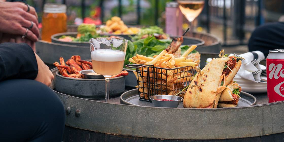 A plate of French fries served with a gourmet burger topped with fresh lettuce, tomato, and onion in a toasted bun, photographed in the cozy dining area of Crazy Raven Bar & Grill.