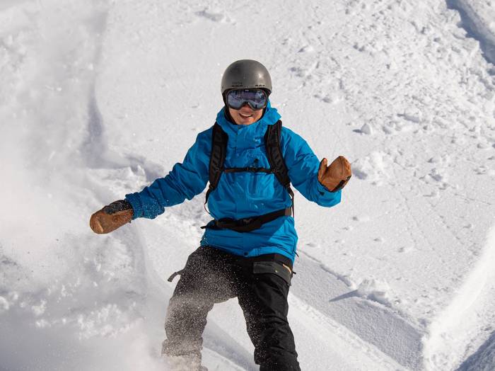 Snowboarder with a blue jacket smiling at the camera.