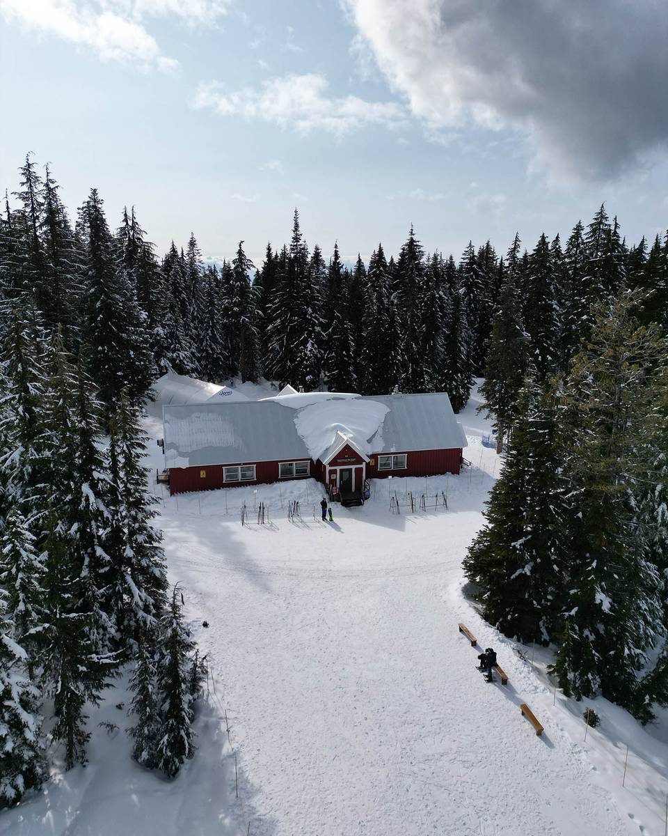 A red commercial lodge nestled nestled in a wintery hemlock, cedar, and fir forest of Hollyburn Ridge