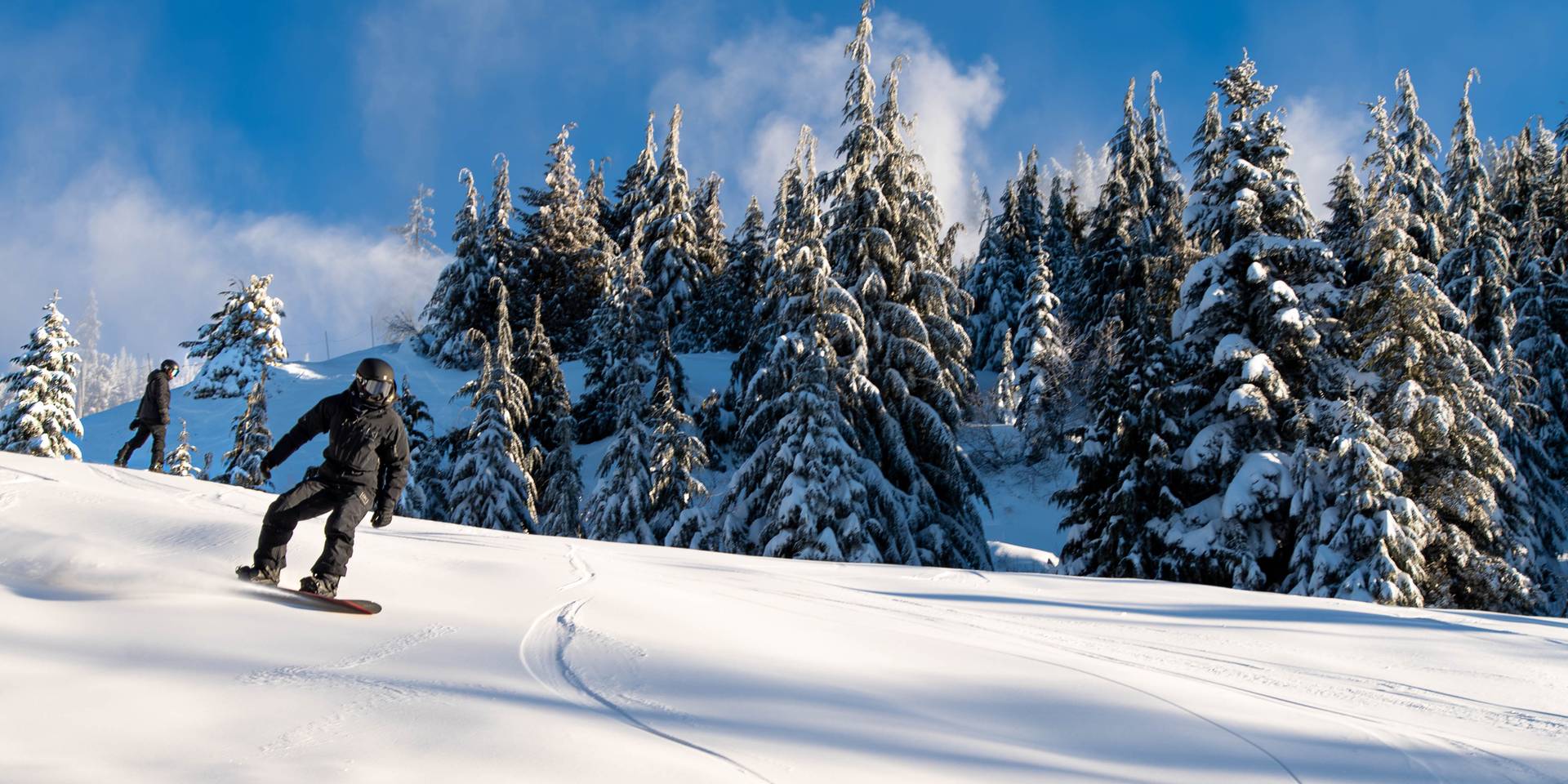 A snowboarder descends a slope with fresh snow.