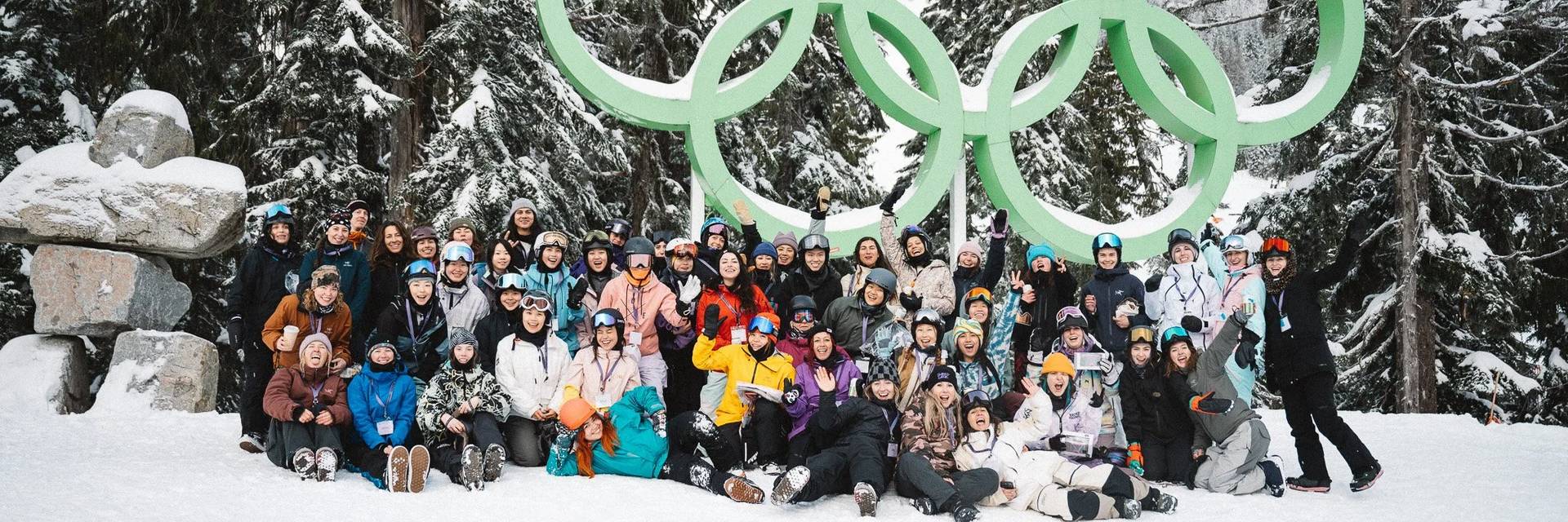 A group of over 30 women pose for a photo in the snow after snowboarding together on Cypress Mountain..