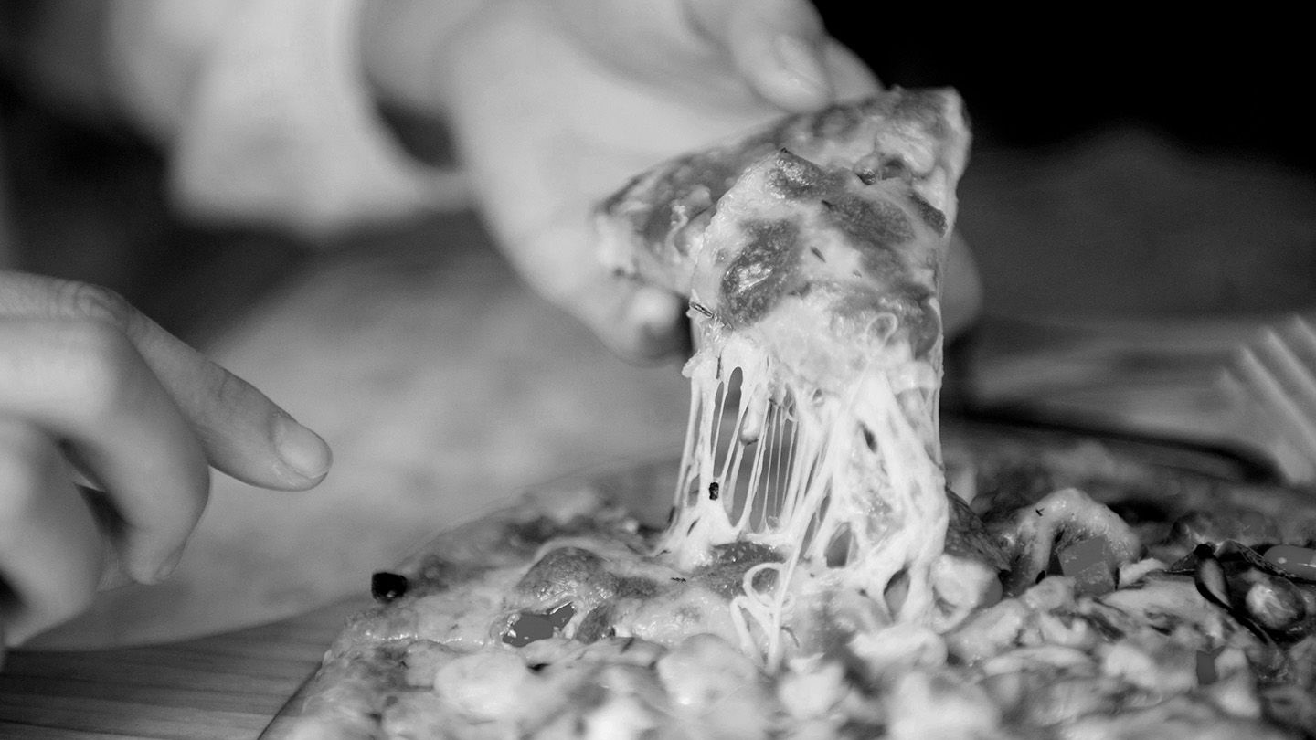 A slice of cheese pizza held by a customer.