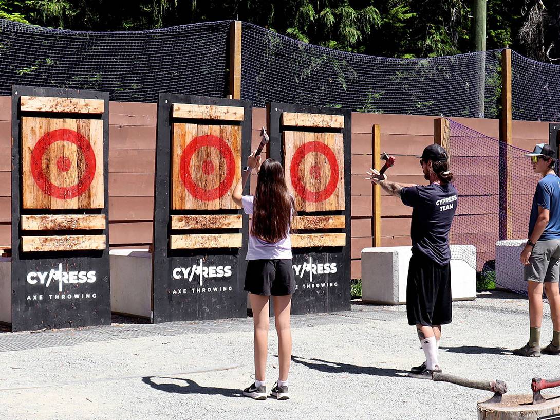 Instructor teaching two participants how to do axe throwing.