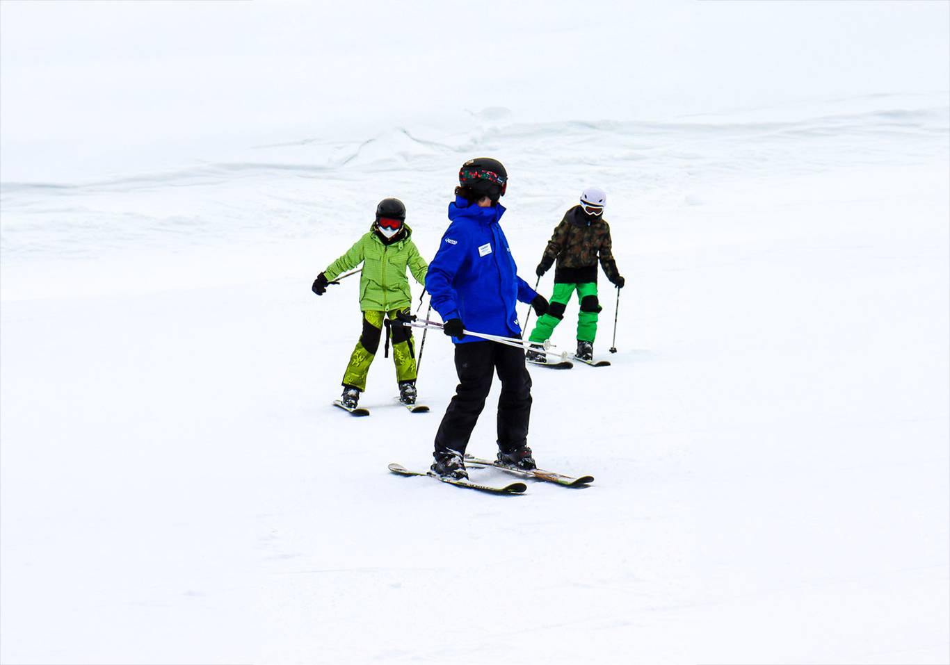 Ski instructor looking back at two child students.