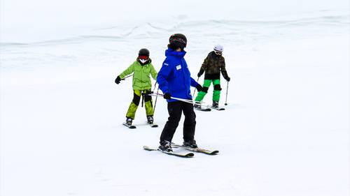 Ski instructor looking back at two child students.