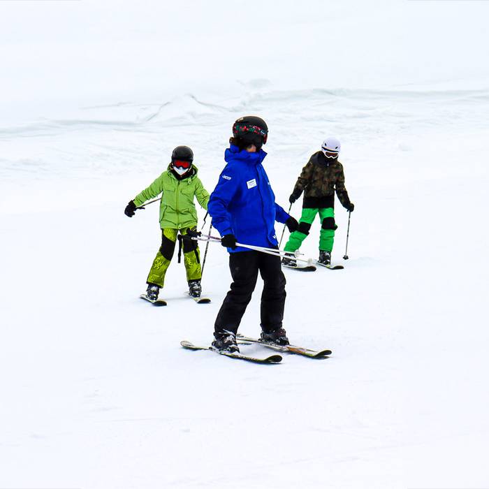 Ski instructor looking back at two child students.