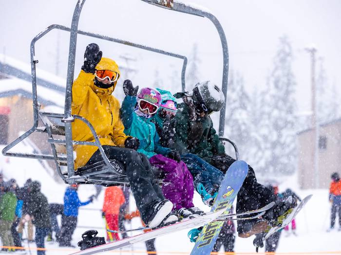 family on chairlift waving