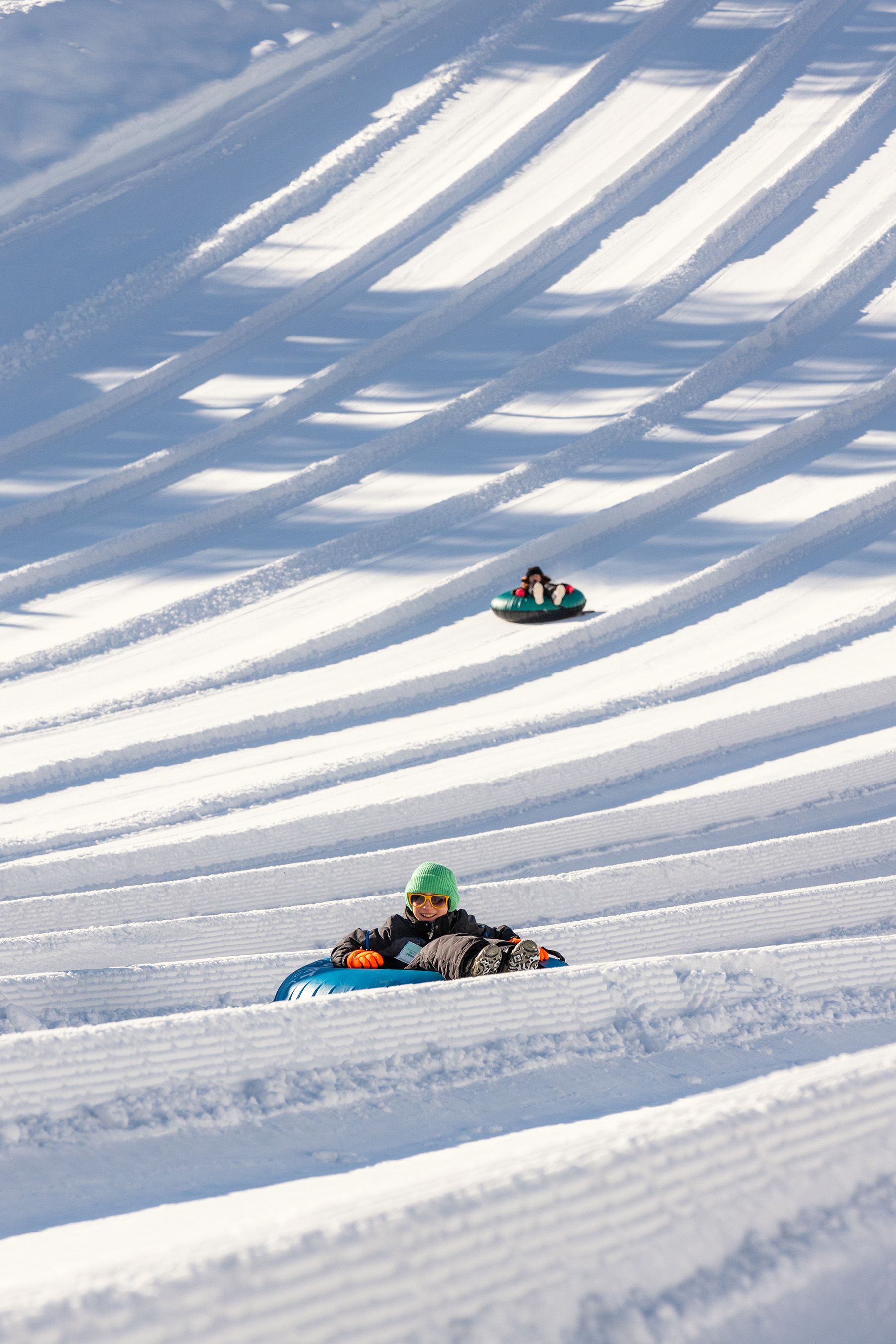 kid sliding down tubing hill with other tubers in the background
