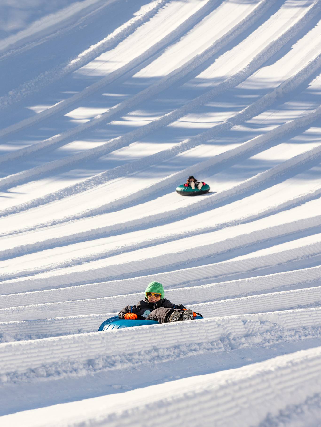 kid sliding down tubing hill with other tubers in the background