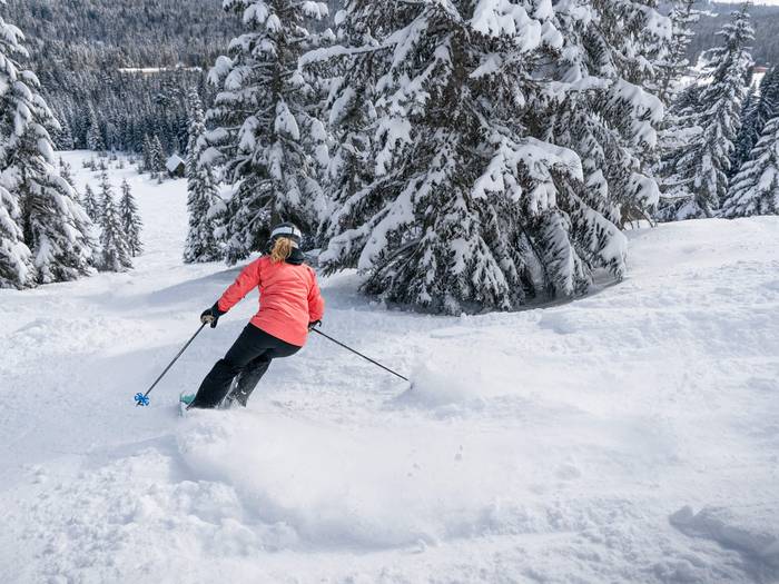 Woman skis powder in mountaineers zone in pink jacket at Summit Central