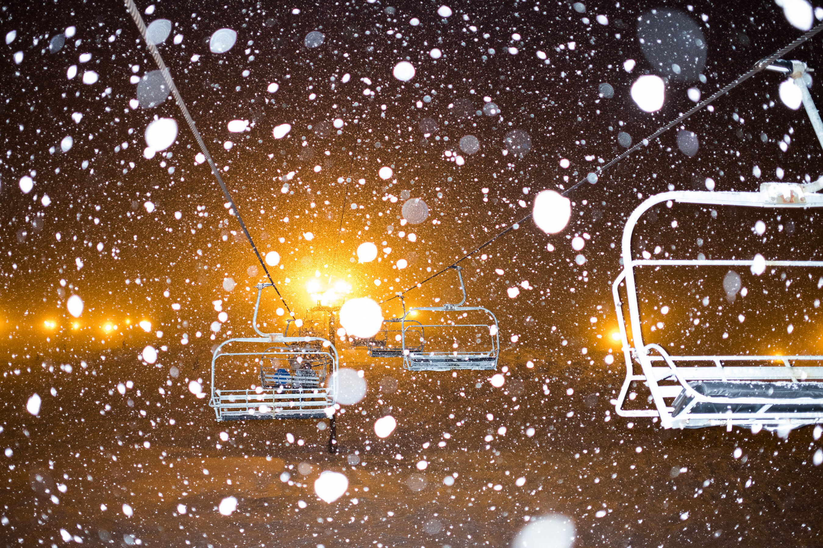 snowy image of chairlifts at night