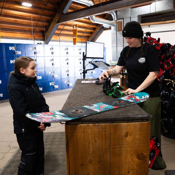 A child getting sized for a snowboard in the rental shop