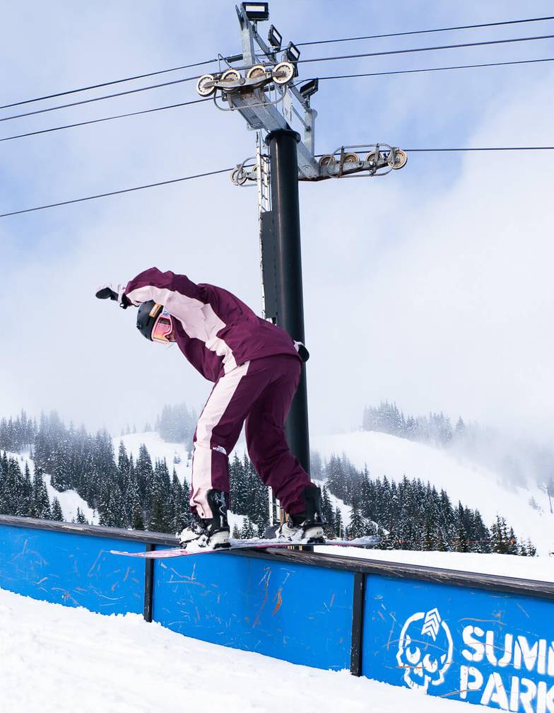 woman snowboarder on down rail in terrain park