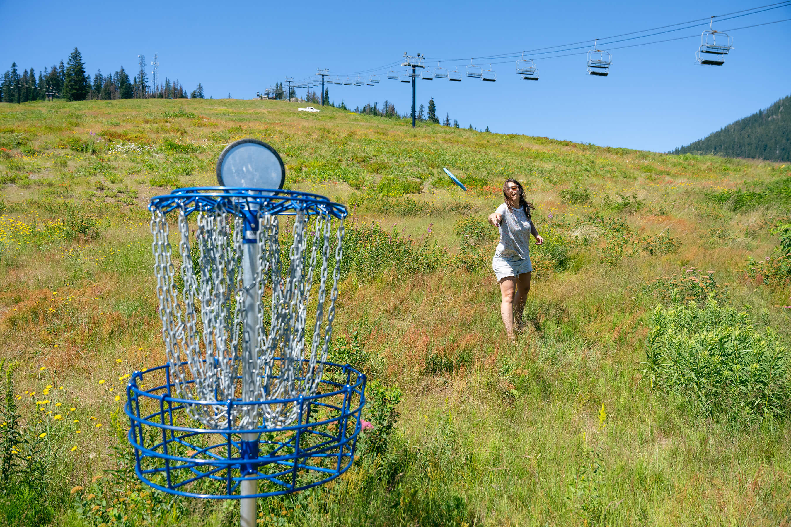 girl throwing disc at disc golf basket