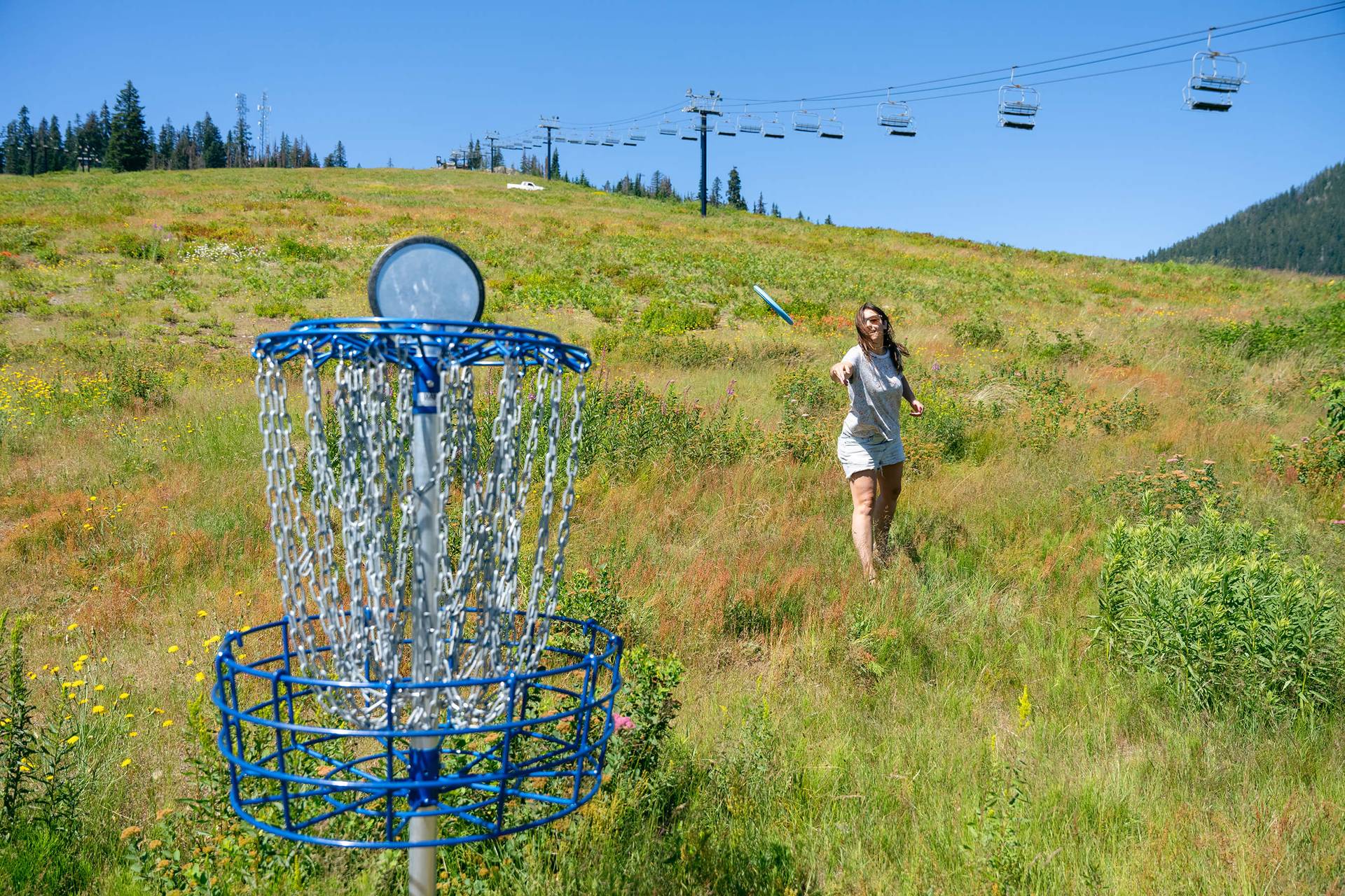 Girl throwing disc at disc golf basket