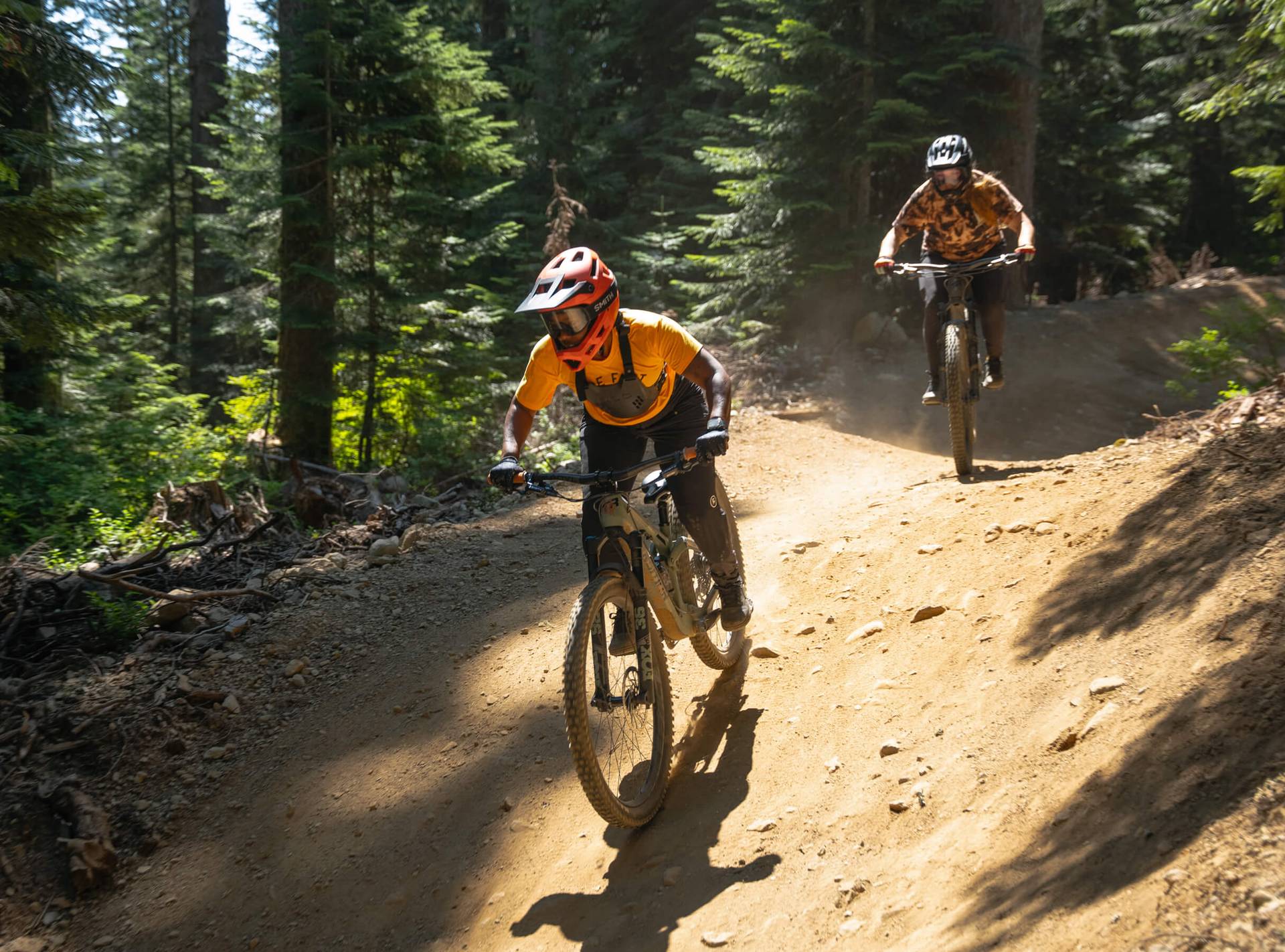 Women on bikes navigate a dusty trail in the summer sunshine