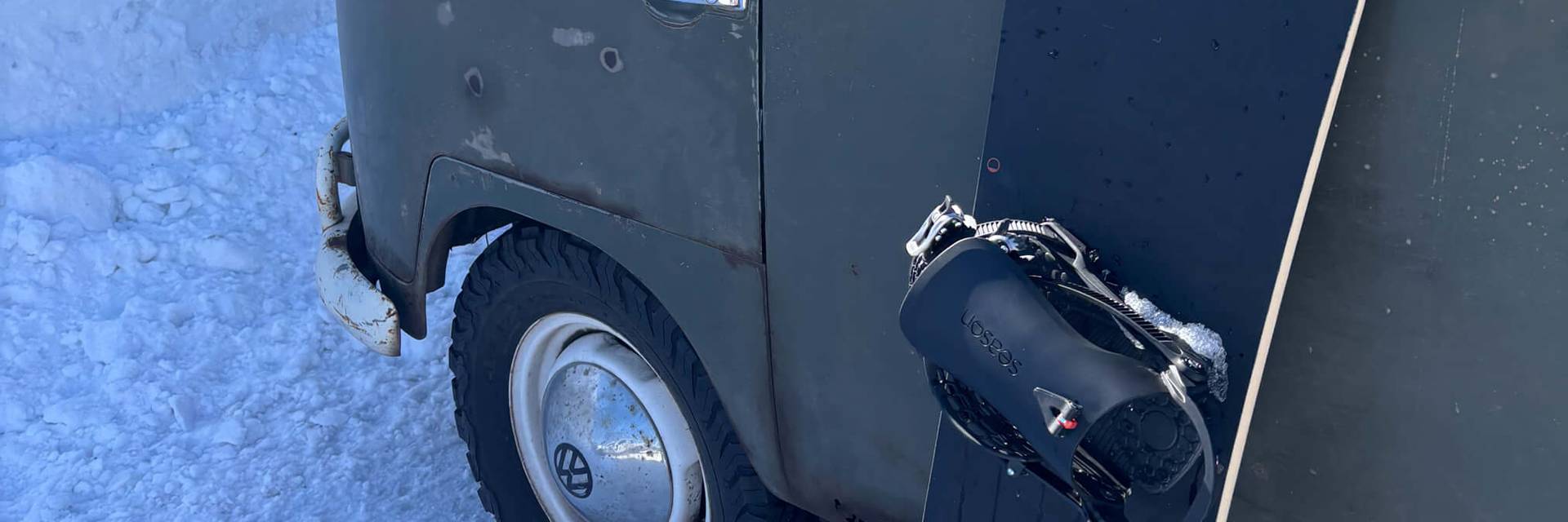 old VW vehicle covered in snow, with snowboard