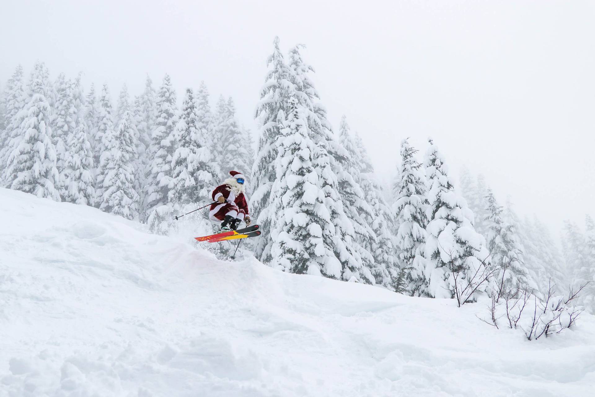 Skier in Santa outfit catches air while flying down slope.