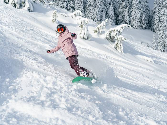 snowboarder in pink outfit in powder
