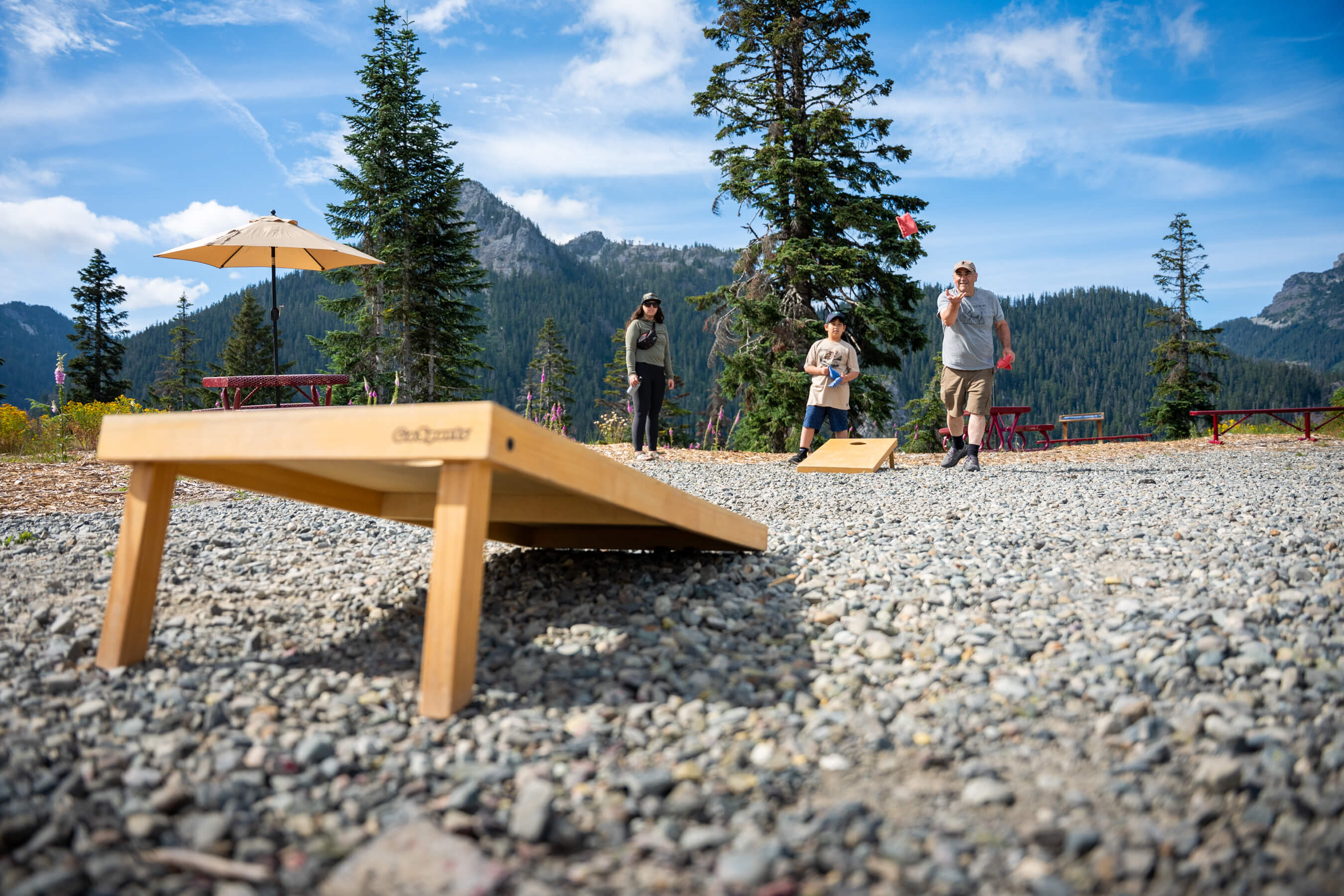 a family playing cornhole at the top of the mountain