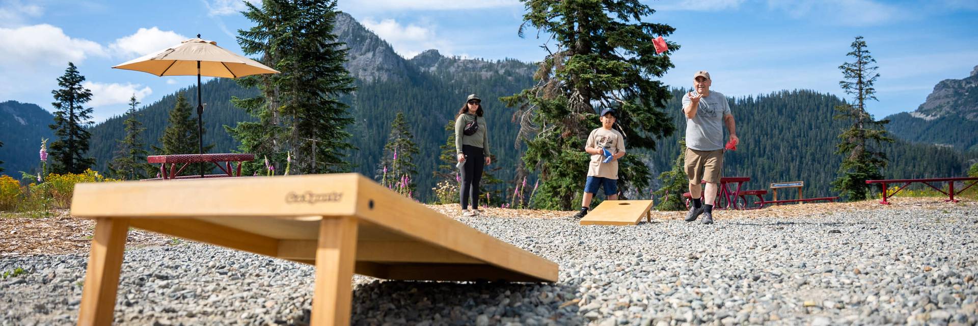 a family playing cornhole at the top of the mountain