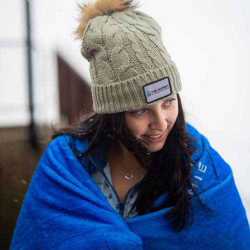 girl wrapped in a blue blanket wearing a tan summit beanie