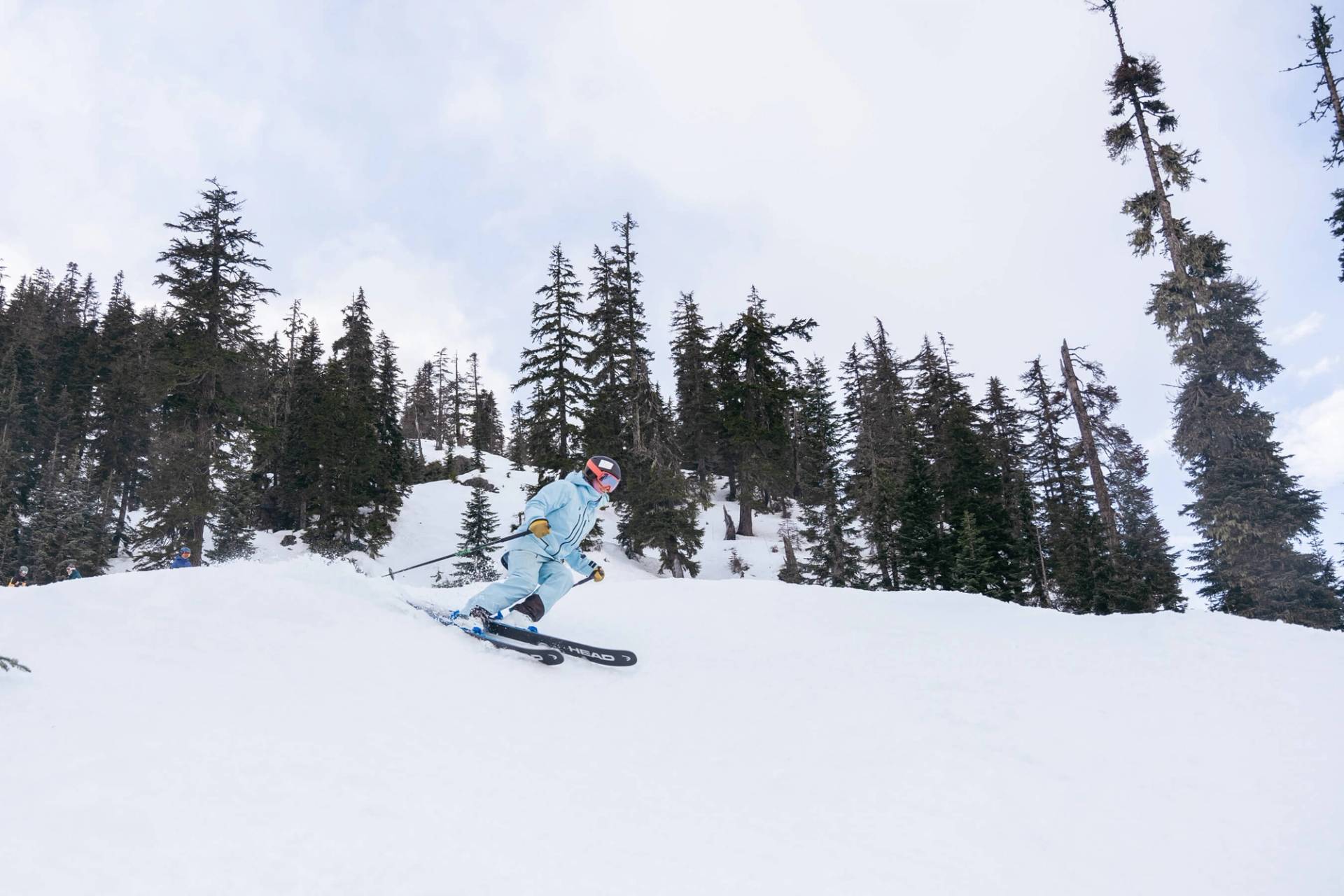 Woman in blue jacket skis steep slope 