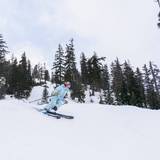 Woman in light blue jacket skis down slope as part of Rippin Chix event at Alpental