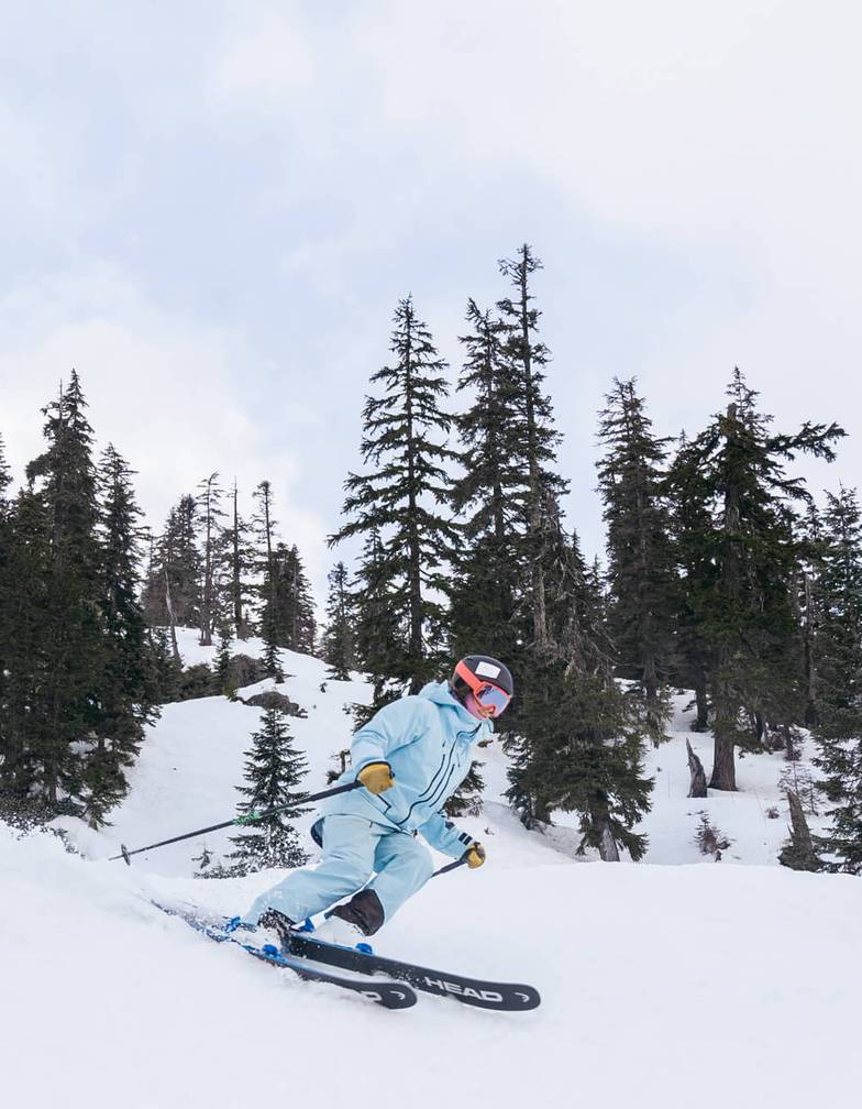 Woman in light blue jacket skis down slope as part of Rippin Chix event at Alpental