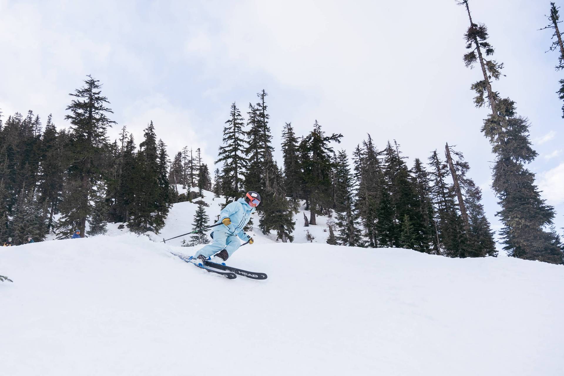 Woman in blue jacket skis steep slope