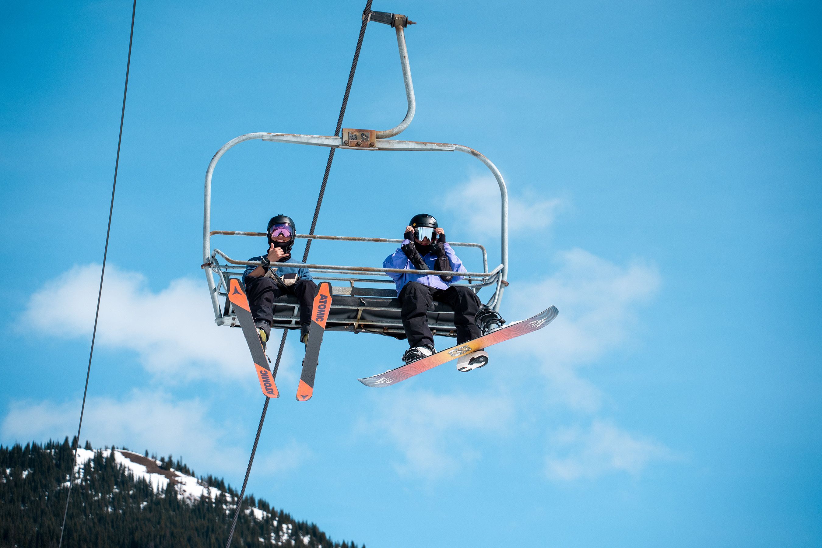 Skier and snowboarder waving from chairlift