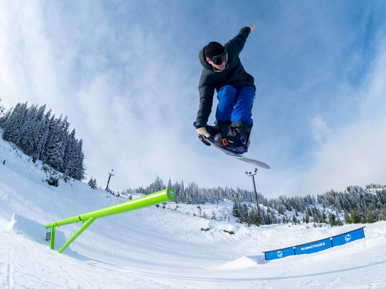 park snowboarder launching off pipe rail